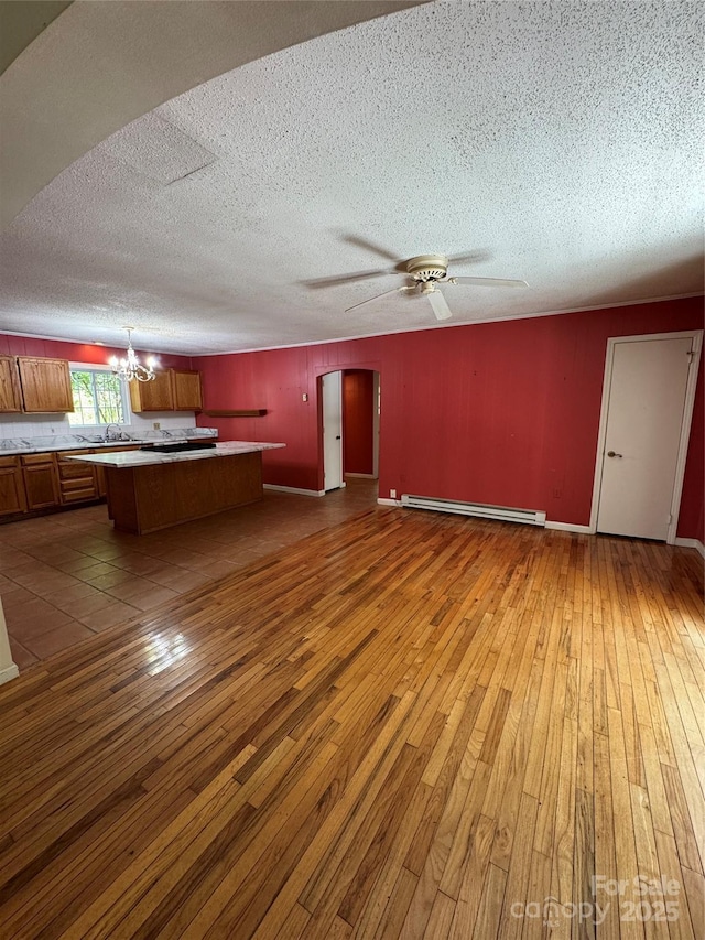 232 Cole Hollow Rd, Newland, NC 28657 - unfurnished living room with a baseboard heating unit, hardwood / wood-style flooring, a chandelier, a textured ceiling, and arched walkways