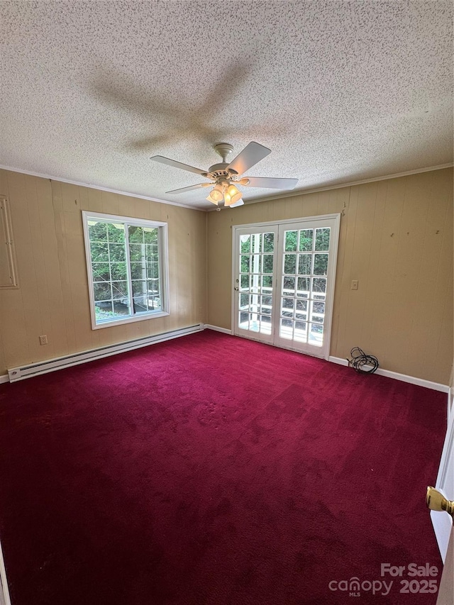232 Cole Hollow Rd, Newland, NC 28657 - carpeted spare room featuring a baseboard radiator, healthy amount of natural light, a ceiling fan, a textured ceiling, and wood walls