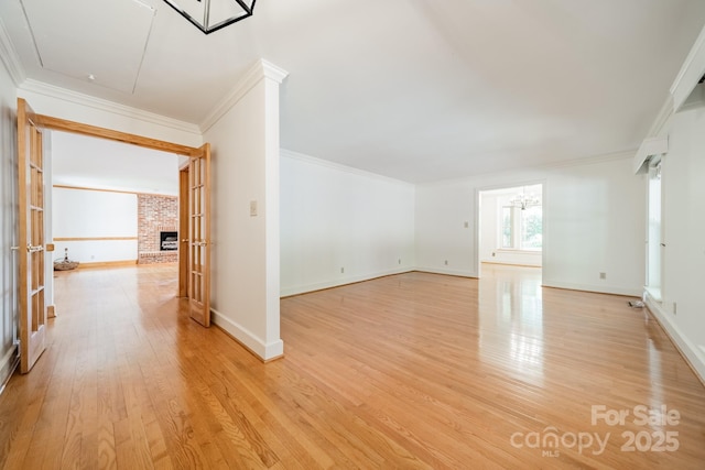 12705 Caldwell Rd, Charlotte, NC 28213 - spare room featuring crown molding, light wood-type flooring, a brick fireplace, and a chandelier