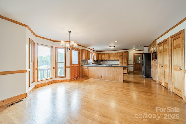 12705 Caldwell Rd, Charlotte, NC 28213 - kitchen featuring dark countertops, a peninsula, a chandelier, light wood-style floors, and crown molding