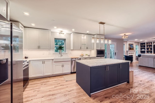 7810 Leisure Ln, Huntersville, NC 28078 - kitchen featuring appliances with stainless steel finishes, a kitchen island, a fireplace, white cabinetry, and recessed lighting