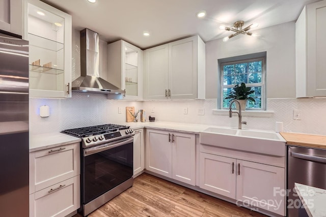 7810 Leisure Ln, Huntersville, NC 28078 - kitchen featuring appliances with stainless steel finishes, wall chimney exhaust hood, light countertops, light wood-style floors, and decorative backsplash
