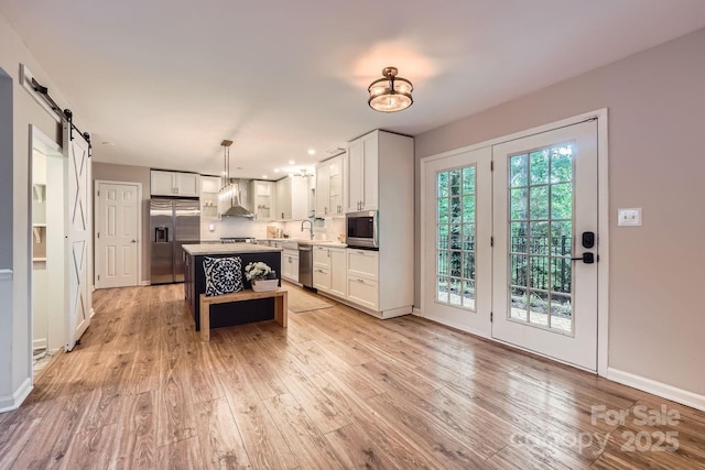 7810 Leisure Ln, Huntersville, NC 28078 - kitchen featuring stainless steel appliances, light wood finished floors, white cabinetry, and a barn door