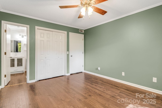 15 Lake Dr Unit D2, Laurel Park, NC 28739 - unfurnished bedroom with wood finished floors, ornamental molding, baseboards, a closet, and a ceiling fan