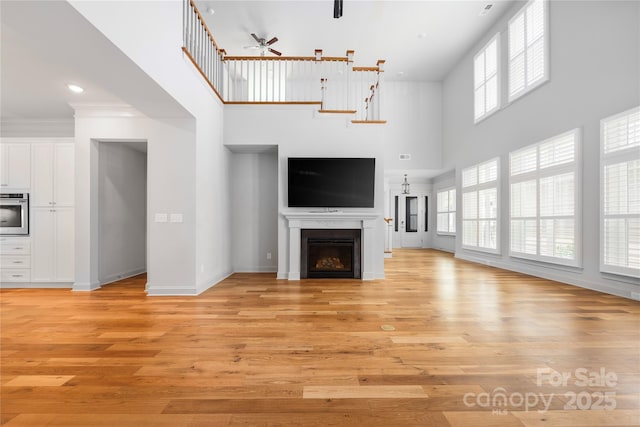 3008 Laney Pond Rd, Matthews, NC 28104 - unfurnished living room featuring a ceiling fan, a towering ceiling, light wood finished floors, and a fireplace