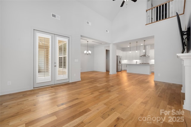 3008 Laney Pond Rd, Matthews, NC 28104 - unfurnished living room with a ceiling fan, light wood finished floors, a chandelier, high vaulted ceiling, and baseboards