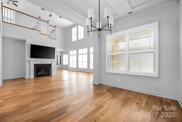 3008 Laney Pond Rd, Matthews, NC 28104 - unfurnished living room with a chandelier, light wood-style flooring, a glass covered fireplace, crown molding, and baseboards