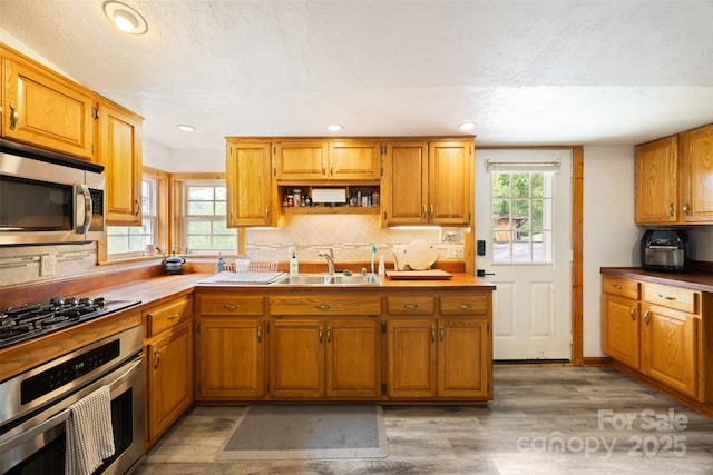 242 Ladd Parsons Rd, Crumpler, NC 28617 - kitchen with stainless steel appliances, a sink, tasteful backsplash, light wood finished floors, and brown cabinetry