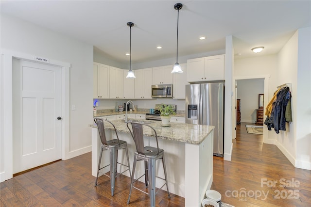 54 Asher Ln, Etowah, NC 28729 - kitchen featuring appliances with stainless steel finishes, a breakfast bar, dark wood finished floors, light stone countertops, and a center island with sink