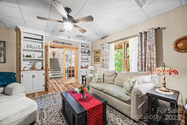 158 Raven Blvd, Lake Lure, NC 28746 - living room with wood finished floors, a ceiling fan, a paneled ceiling, built in features, and stairs