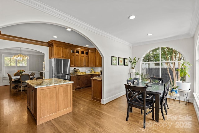 1619 Providence Rd, Charlotte, NC 28207 - kitchen with freestanding refrigerator, arched walkways, brown cabinetry, light stone counters, and glass insert cabinets
