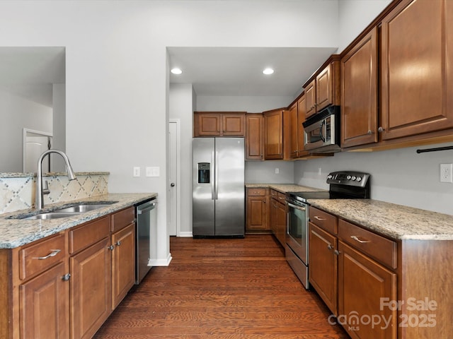 1660 Beleek Ridge Ln, Lake Wylie, SC 29710 - kitchen featuring appliances with stainless steel finishes, a sink, light stone counters, dark wood-type flooring, and brown cabinets