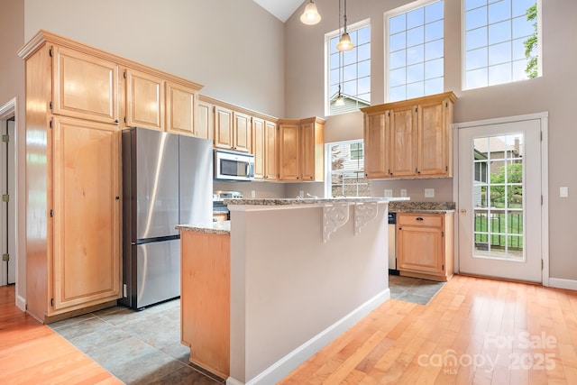 2695 Queens Rd, Lincolnton, NC 28092 - kitchen with appliances with stainless steel finishes, light brown cabinetry, a towering ceiling, light wood-style flooring, and a center island