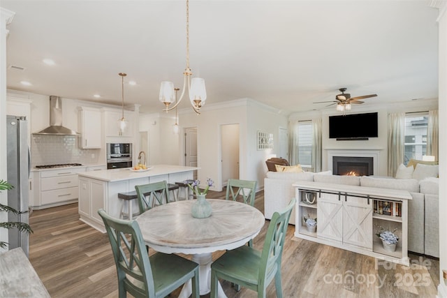 635 R L Stowe Rd, Belmont, NC 28012 - dining space featuring light wood finished floors, a lit fireplace, ceiling fan, crown molding, and recessed lighting