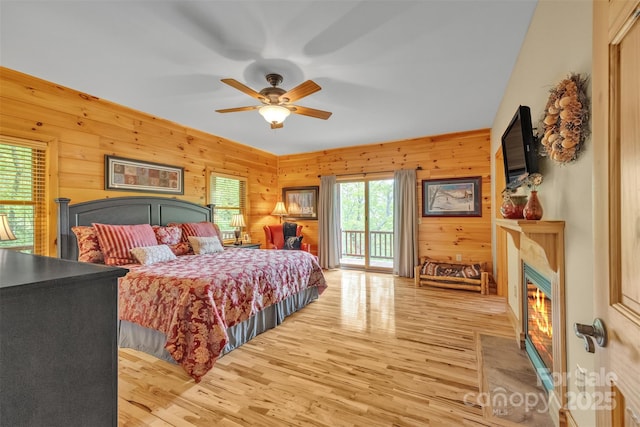 265 Laurel Mountain Estates Dr, Todd, NC 28684 - bedroom featuring access to exterior, a fireplace with flush hearth, light wood finished floors, wooden walls, and a ceiling fan