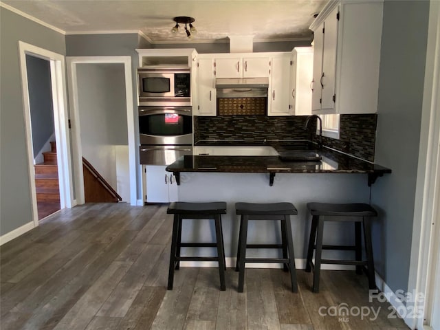 1300 Montgomery Ave, Albemarle, NC 28001 - kitchen with stainless steel appliances, a warming drawer, dark countertops, ornamental molding, and white cabinetry