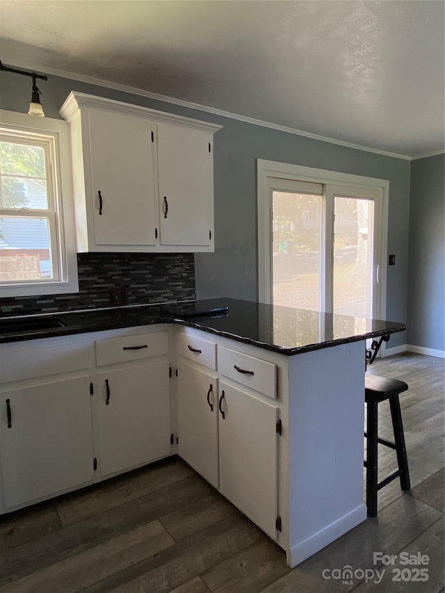 1300 Montgomery Ave, Albemarle, NC 28001 - kitchen featuring crown molding, a peninsula, white cabinetry, plenty of natural light, and dark wood-style flooring