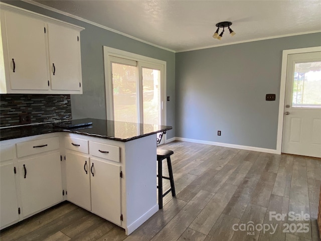 1300 Montgomery Ave, Albemarle, NC 28001 - kitchen featuring a peninsula, ornamental molding, wood finished floors, white cabinetry, and decorative backsplash