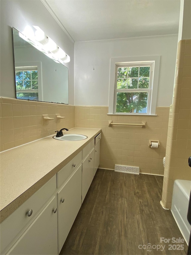 1300 Montgomery Ave, Albemarle, NC 28001 - bathroom featuring tile walls, vanity, wood finished floors, healthy amount of natural light, and wainscoting