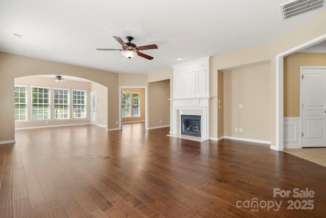 56119 Finches Ct, Indian Land, SC 29707 - unfurnished living room featuring a ceiling fan, wood finished floors, arched walkways, and a large fireplace