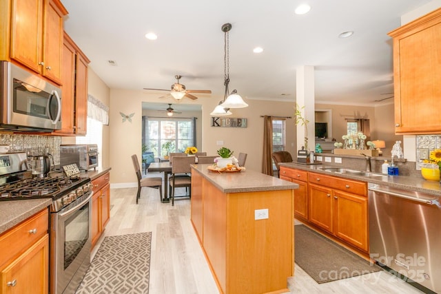 1006 Apogee Dr, Indian Trail, NC 28079 - kitchen featuring appliances with stainless steel finishes, a ceiling fan, a kitchen island, light wood-style flooring, and backsplash