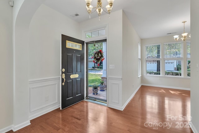5963 Pale Moss Ln, Charlotte, NC 28269 - entrance foyer with a chandelier, wood finished floors, a wainscoted wall, arched walkways, and a decorative wall