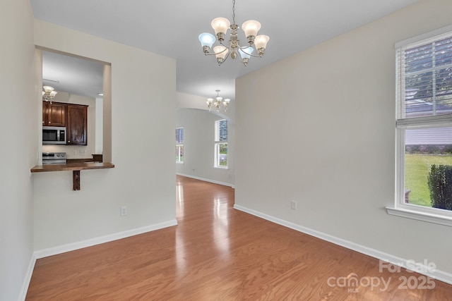 5963 Pale Moss Ln, Charlotte, NC 28269 - spare room with a chandelier, light wood-type flooring, and baseboards