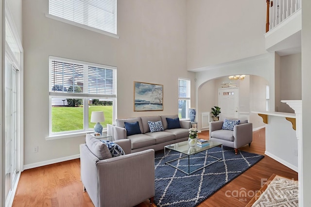 5963 Pale Moss Ln, Charlotte, NC 28269 - living area featuring arched walkways, a high ceiling, wood finished floors, baseboards, and a chandelier