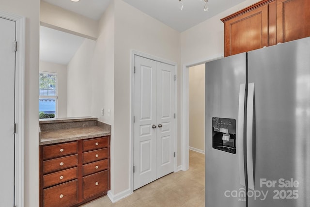 5963 Pale Moss Ln, Charlotte, NC 28269 - kitchen with stainless steel fridge with ice dispenser, baseboards, and brown cabinets