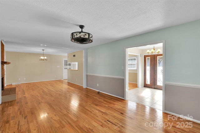 2326 Horseshoe Bend Rd NE, Hickory, NC 28601 - unfurnished living room featuring a chandelier, light wood-style floors, a brick fireplace, and a textured ceiling