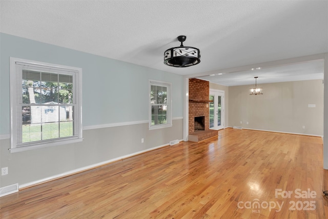 2326 Horseshoe Bend Rd NE, Hickory, NC 28601 - unfurnished living room featuring light wood-style floors, a fireplace, a chandelier, and a textured ceiling