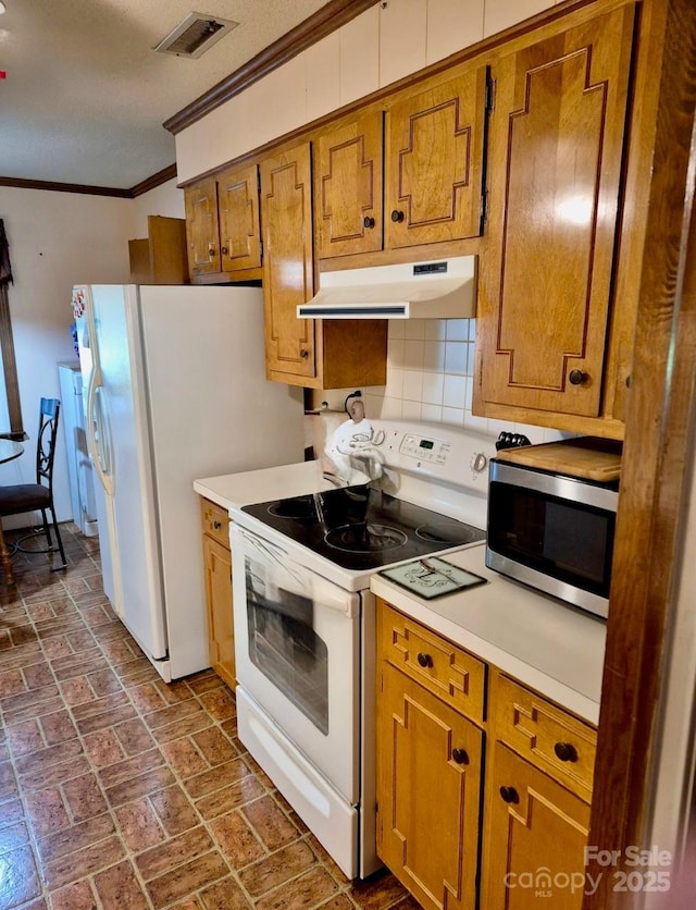 8616 Fallsdale Dr, Charlotte, NC 28214 - kitchen with white appliances, under cabinet range hood, crown molding, brown cabinets, and brick patterned floors