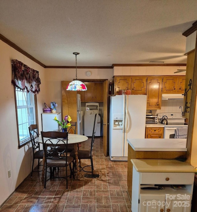 8616 Fallsdale Dr, Charlotte, NC 28214 - kitchen with white appliances, under cabinet range hood, brown cabinetry, light countertops, and pendant lighting