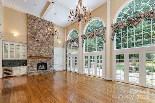 517 Kingsdown Ct, Waxhaw, NC 28173 - unfurnished living room with a towering ceiling, wine cooler, a chandelier, wood finished floors, and ornamental molding
