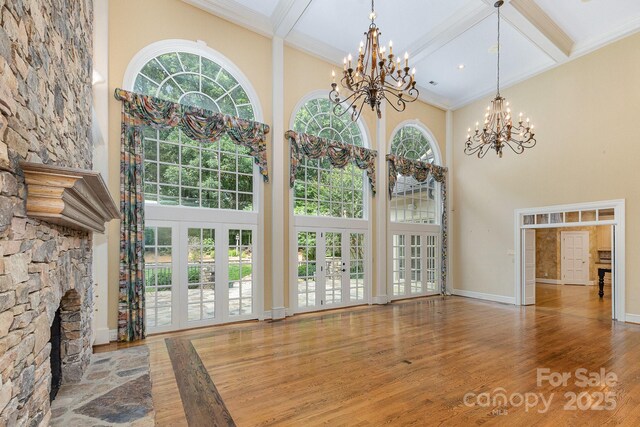 517 Kingsdown Ct, Waxhaw, NC 28173 - unfurnished living room with a towering ceiling, a chandelier, wood finished floors, beam ceiling, and coffered ceiling