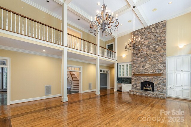 517 Kingsdown Ct, Waxhaw, NC 28173 - unfurnished living room with a chandelier, a towering ceiling, a fireplace, wood finished floors, and stairs