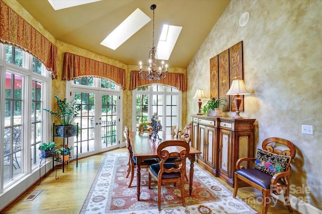 517 Kingsdown Ct, Waxhaw, NC 28173 - dining area with a skylight, a chandelier, light wood-type flooring, high vaulted ceiling, and french doors