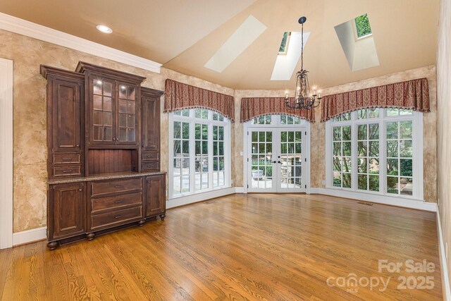 517 Kingsdown Ct, Waxhaw, NC 28173 - unfurnished dining area featuring a skylight, a chandelier, light wood-type flooring, plenty of natural light, and vaulted ceiling