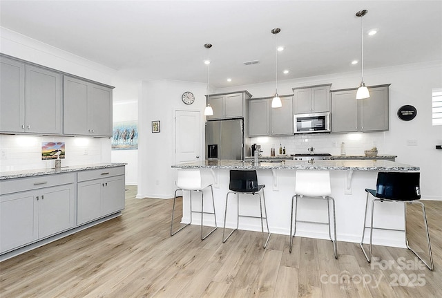 13140 Sudwick Ln, Charlotte, NC 28278 - kitchen featuring stainless steel appliances, gray cabinets, backsplash, light wood finished floors, and a breakfast bar area