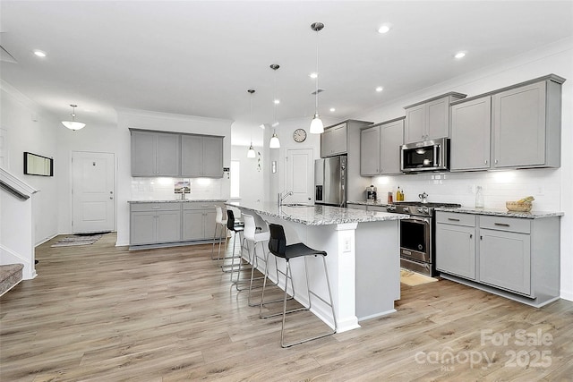 13140 Sudwick Ln, Charlotte, NC 28278 - kitchen featuring appliances with stainless steel finishes, gray cabinets, a sink, backsplash, and a breakfast bar