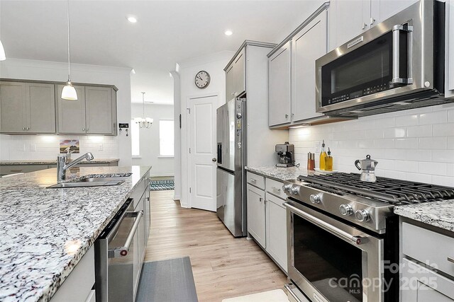 13140 Sudwick Ln, Charlotte, NC 28278 - kitchen featuring appliances with stainless steel finishes, a sink, gray cabinetry, light wood finished floors, and tasteful backsplash