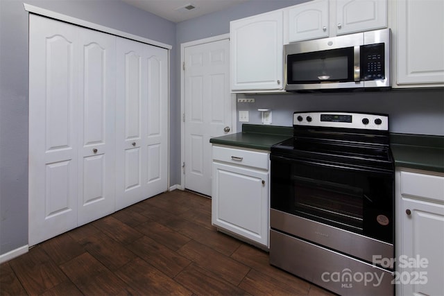 7623 Monarch Birch Ln, Charlotte, NC 28215 - kitchen featuring stainless steel appliances, dark countertops, white cabinets, dark wood-style floors, and baseboards