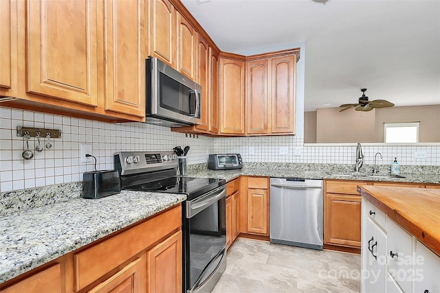 1817 Tradd Ave, Clover, SC 29710 - kitchen featuring appliances with stainless steel finishes, a sink, a ceiling fan, decorative backsplash, and light stone countertops