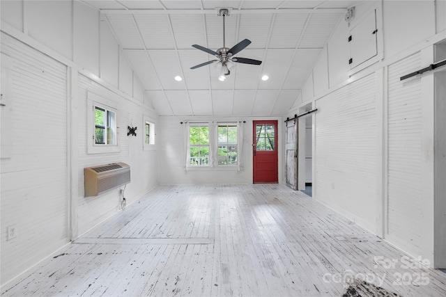 220 W College St, Black Mountain, NC 28711 - unfurnished living room featuring a barn door, a wall mounted air conditioner, hardwood / wood-style flooring, ceiling fan, and lofted ceiling