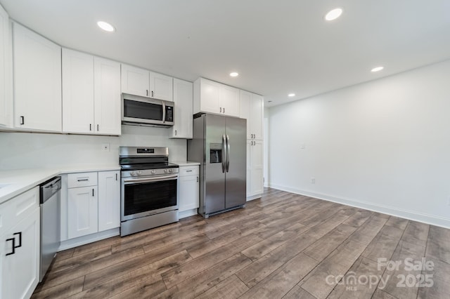 3608 Crestridge Dr, Charlotte, NC 28217 - kitchen featuring appliances with stainless steel finishes, wood finished floors, light countertops, white cabinetry, and recessed lighting