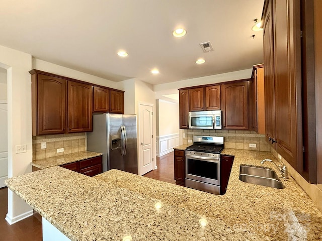 1304 Ridge Haven Rd, Waxhaw, NC 28173 - kitchen with appliances with stainless steel finishes, a peninsula, light stone counters, decorative backsplash, and recessed lighting