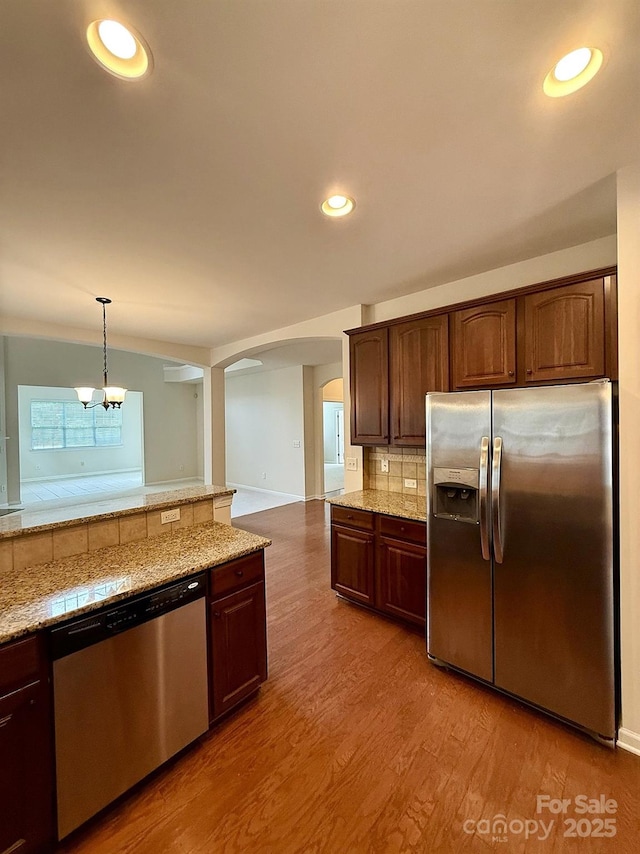 1304 Ridge Haven Rd, Waxhaw, NC 28173 - kitchen featuring appliances with stainless steel finishes, arched walkways, backsplash, light wood-style flooring, and a chandelier