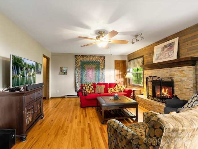 2981 Heath Peak Rd, Waynesville, NC 28785 - living area featuring a baseboard heating unit, a ceiling fan, light wood finished floors, a stone fireplace, and baseboards