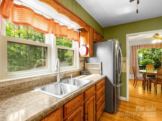 2981 Heath Peak Rd, Waynesville, NC 28785 - kitchen featuring a sink, a ceiling fan, brown cabinets, freestanding refrigerator, and light wood-style floors