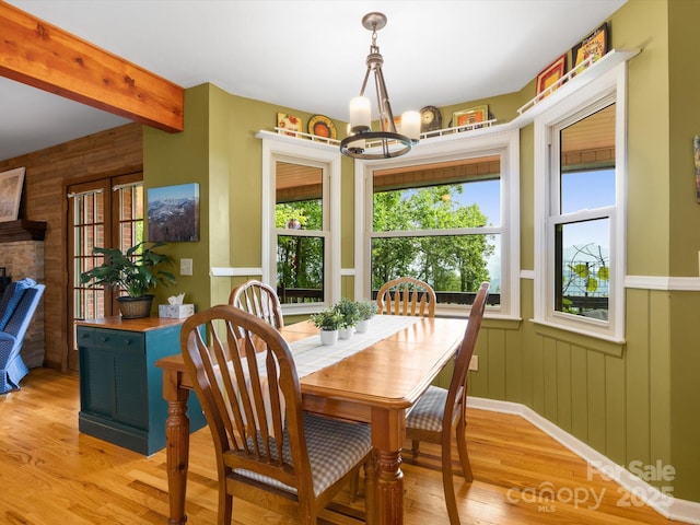 2981 Heath Peak Rd, Waynesville, NC 28785 - dining space with plenty of natural light, a chandelier, light wood-type flooring, wood walls, and wainscoting